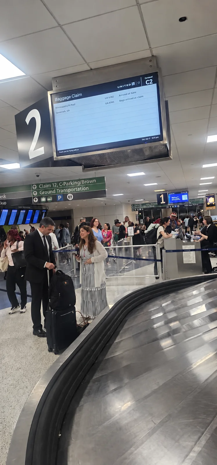 Chauffeur helping a traveler with suitcases beside an IAH baggage carousel