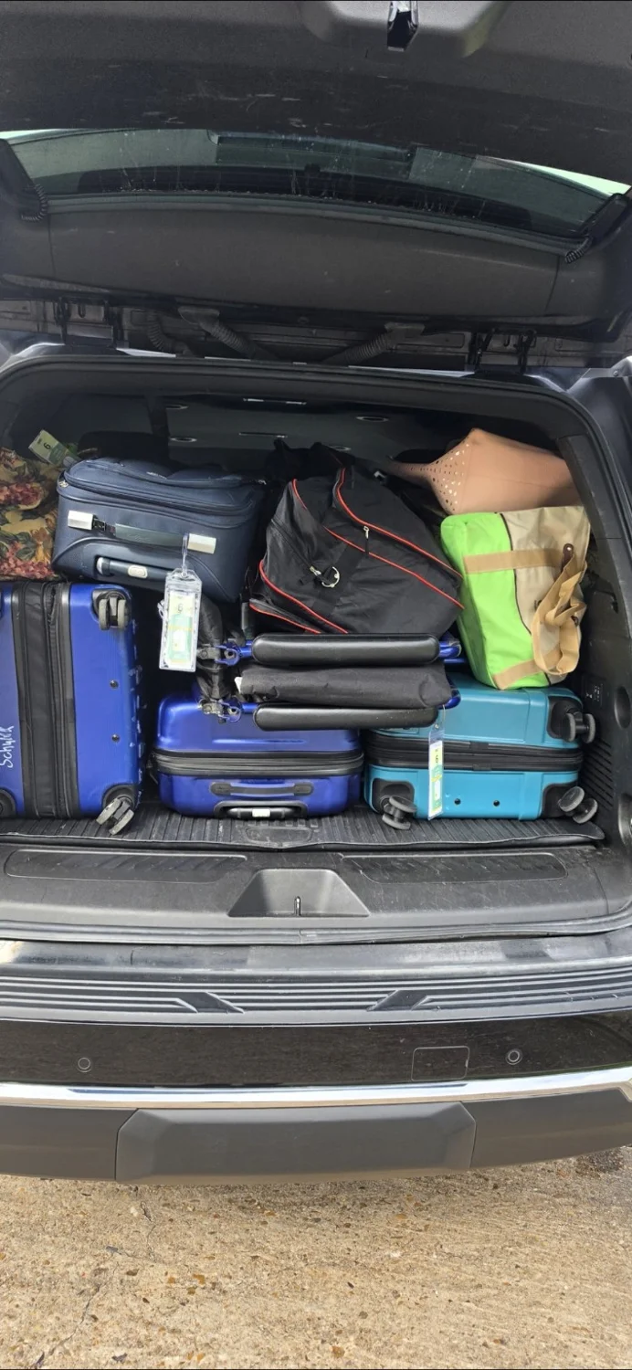SUV cargo area packed with suitcases, a duffel and tote bags for an airport transfer