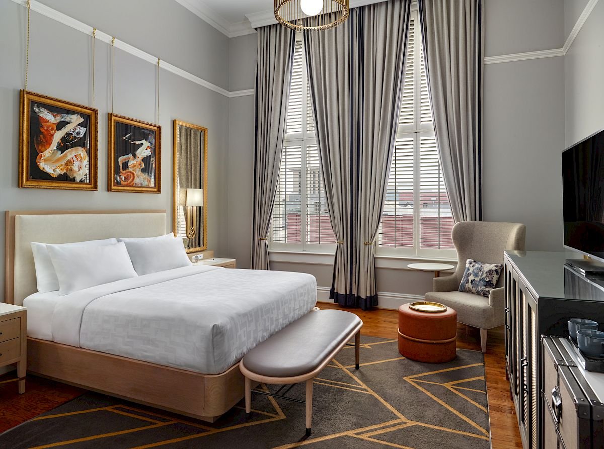 Guest room at The Tremont House with tall windows and a king bed