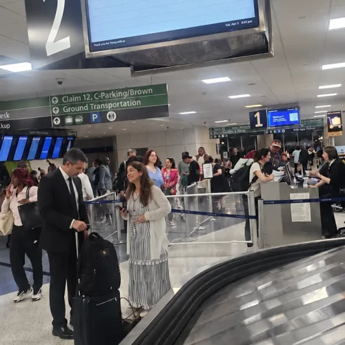 Chauffeur helping a traveler with suitcases beside an IAH baggage carousel