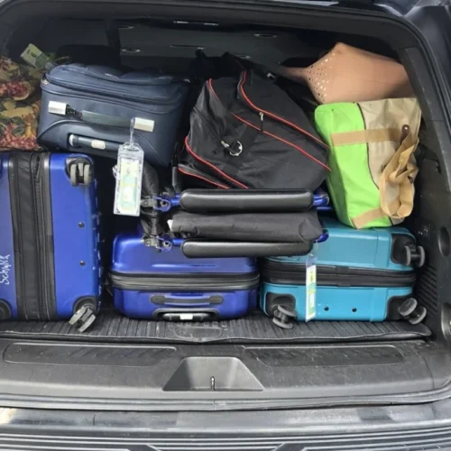 SUV cargo area packed with suitcases, a duffel and tote bags for an airport transfer